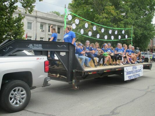 GYAA Volleyball teams and coaches ride on a float adorned with a volleyball net.