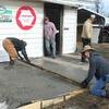 James Clabough and Ricky Cooper smooth the freshly poured patio while Bernard Daniel and owner, Brian Gray, look on.